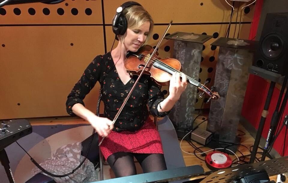 Recording studio sessions with headphones on her ears and the violin in her arms